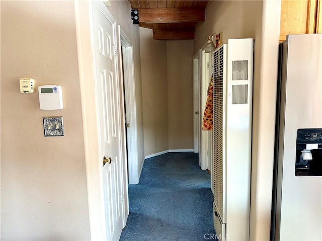 hall featuring dark colored carpet, beam ceiling, and wood ceiling