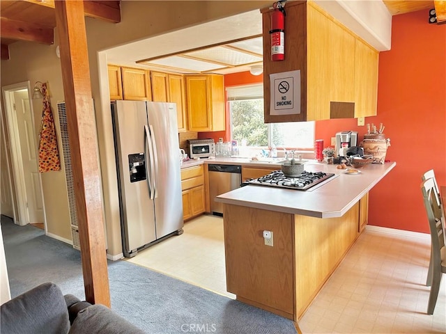 kitchen with kitchen peninsula, sink, beamed ceiling, and stainless steel appliances