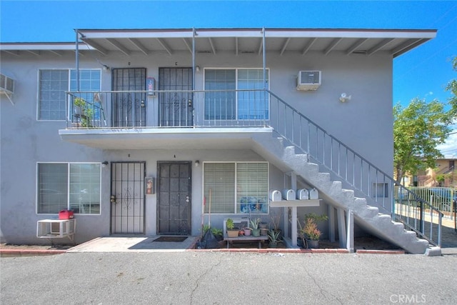 view of front of property with a balcony and a wall unit AC