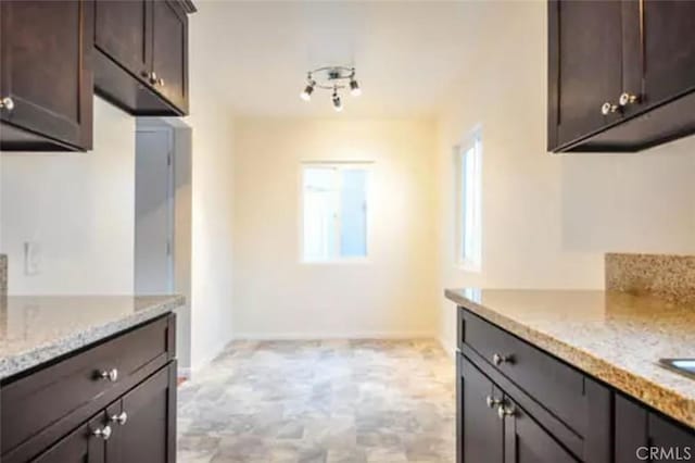 kitchen featuring dark brown cabinets and light stone counters