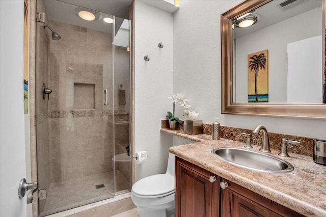 bathroom featuring a shower with shower door, vanity, and toilet