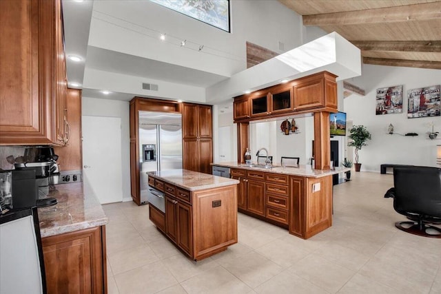 kitchen with light stone counters, stainless steel appliances, beamed ceiling, and a kitchen island