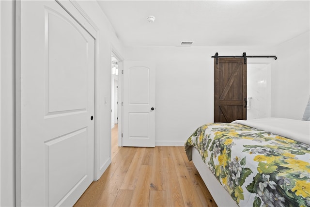 bedroom with a barn door and light hardwood / wood-style floors