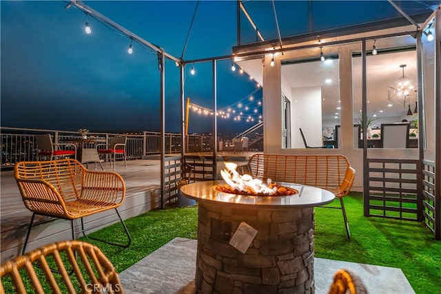 patio at night featuring a yard and a fire pit