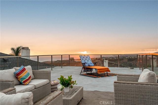 patio terrace at dusk featuring a balcony and an outdoor living space