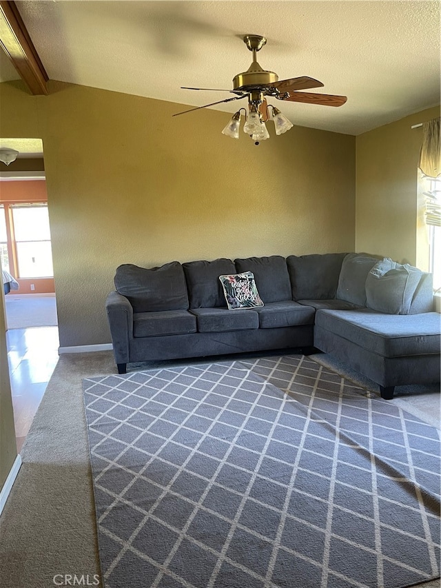 living room featuring vaulted ceiling with beams, ceiling fan, and carpet