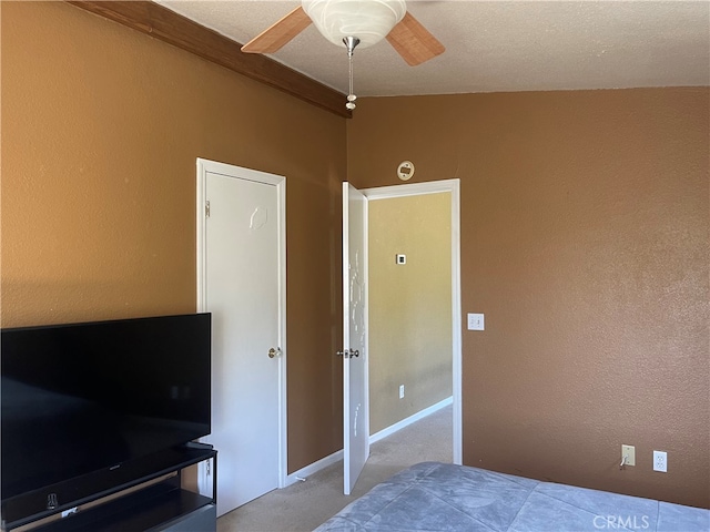 carpeted bedroom featuring ceiling fan and a textured ceiling