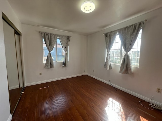 unfurnished bedroom with dark hardwood / wood-style floors and a closet