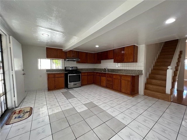 kitchen with sink, stainless steel range oven, a textured ceiling, and decorative backsplash