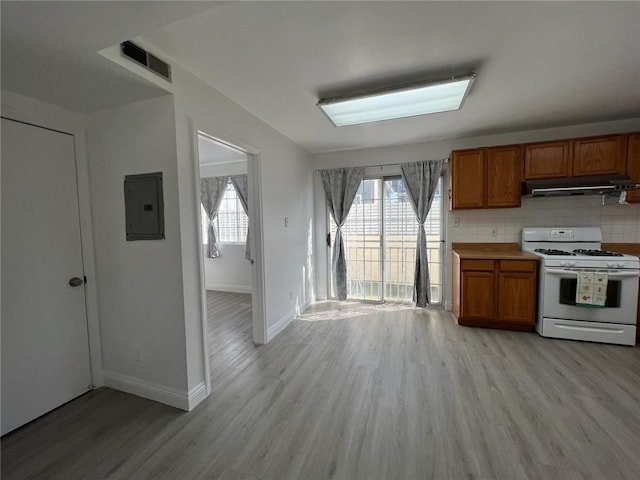 kitchen featuring plenty of natural light, light hardwood / wood-style flooring, electric panel, and white gas range oven