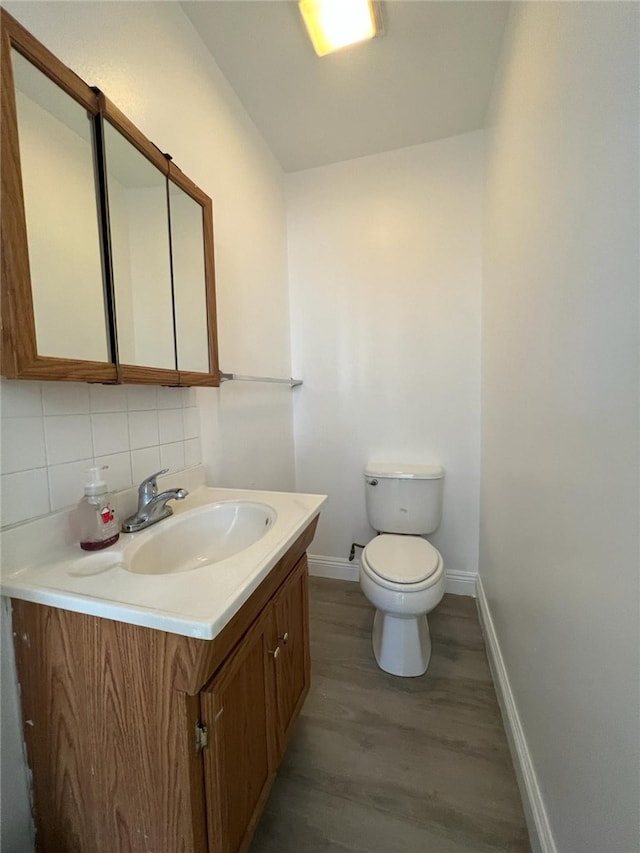 bathroom with vanity, wood-type flooring, toilet, and decorative backsplash