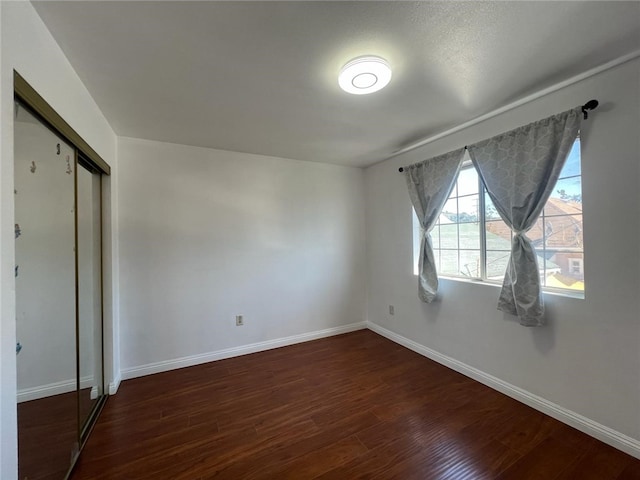 unfurnished bedroom featuring dark hardwood / wood-style floors and a closet