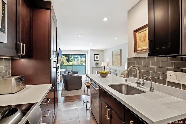 kitchen featuring tile patterned floors, a kitchen breakfast bar, sink, decorative backsplash, and stainless steel appliances