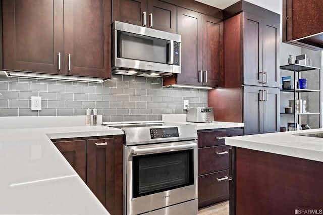 kitchen featuring decorative backsplash, light stone counters, and appliances with stainless steel finishes