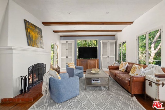 living room featuring wood-type flooring, beamed ceiling, a fireplace, and plenty of natural light