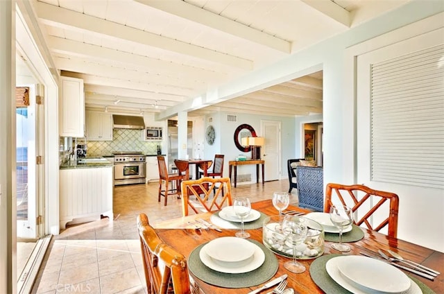 dining room with sink, beamed ceiling, and light tile patterned floors