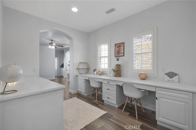 office space featuring ceiling fan, dark hardwood / wood-style floors, and built in desk