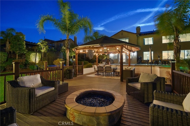 deck at night with an outdoor living space with a fire pit and a gazebo