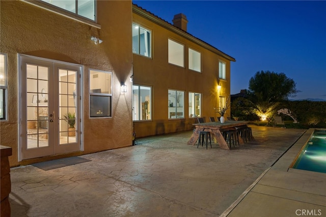 back house at night with french doors and a patio