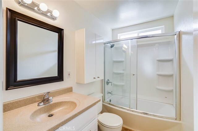 full bathroom featuring vanity, bath / shower combo with glass door, and toilet