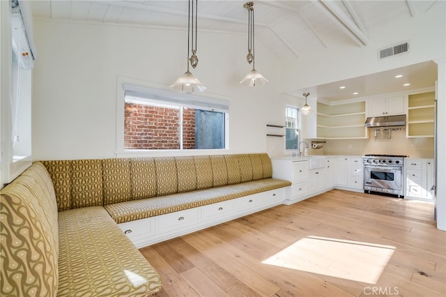 unfurnished living room with beamed ceiling, light wood-type flooring, high vaulted ceiling, and sink