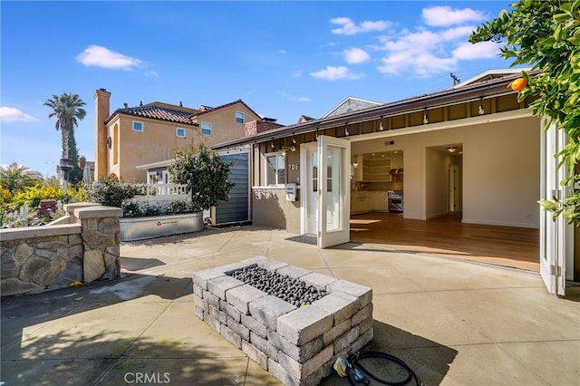 rear view of property with a patio and a fire pit