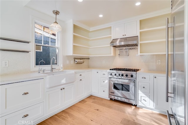 kitchen with high end appliances, sink, decorative light fixtures, white cabinets, and light hardwood / wood-style floors