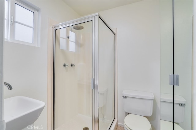 bathroom with toilet, a shower with shower door, and sink