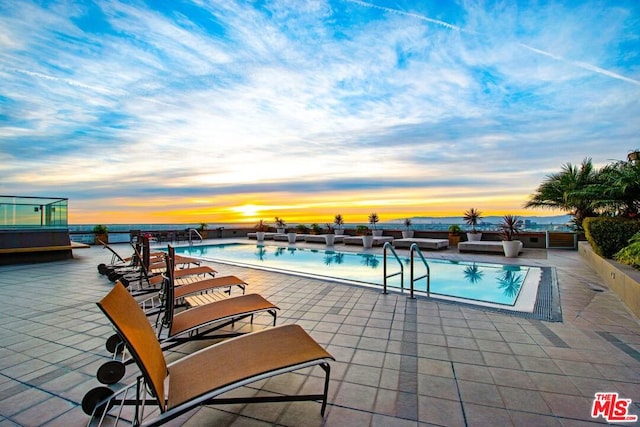 pool at dusk featuring a patio area