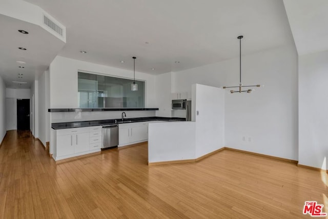 kitchen featuring sink, appliances with stainless steel finishes, white cabinets, light hardwood / wood-style flooring, and decorative light fixtures