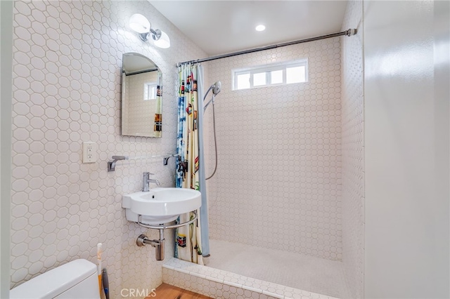 bathroom featuring curtained shower, toilet, sink, and tile walls