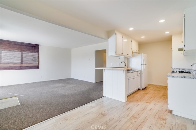 kitchen featuring sink, light hardwood / wood-style flooring, white refrigerator, kitchen peninsula, and white cabinets