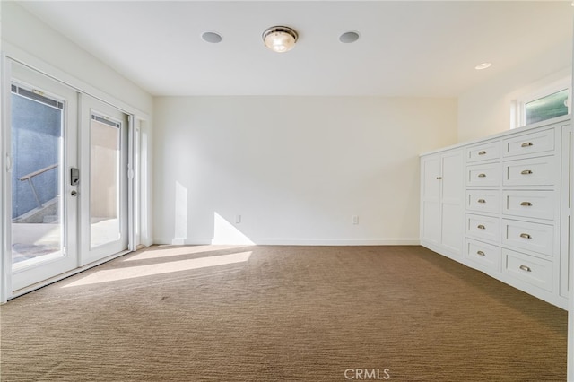 unfurnished room with french doors, a healthy amount of sunlight, and dark carpet