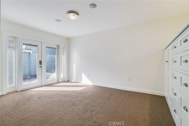 spare room featuring dark colored carpet and french doors