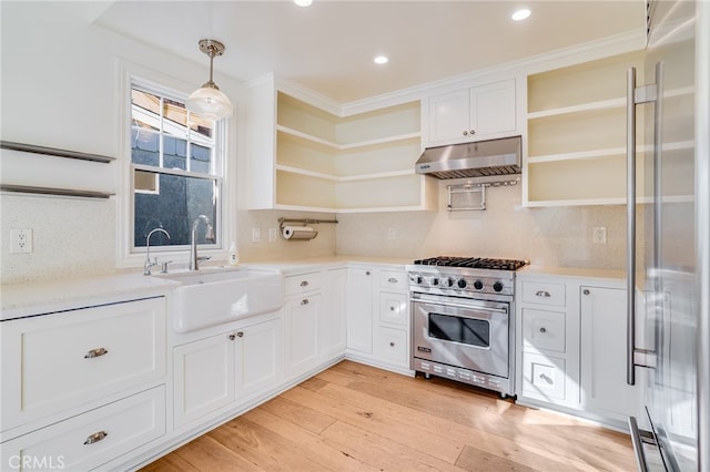 kitchen with high quality appliances, white cabinets, sink, hanging light fixtures, and light hardwood / wood-style flooring