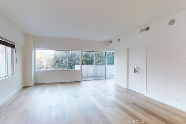 unfurnished room with light wood finished floors, baseboards, and visible vents