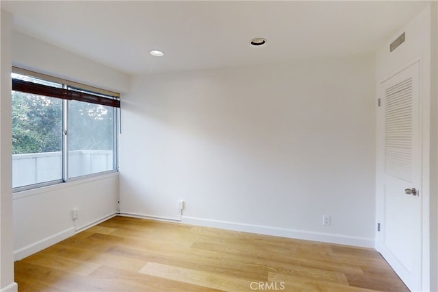 empty room featuring recessed lighting, baseboards, and light wood finished floors