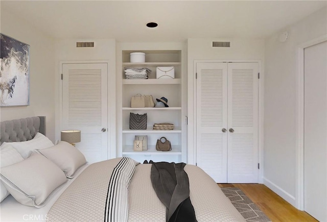 bedroom featuring a closet, visible vents, baseboards, and wood finished floors