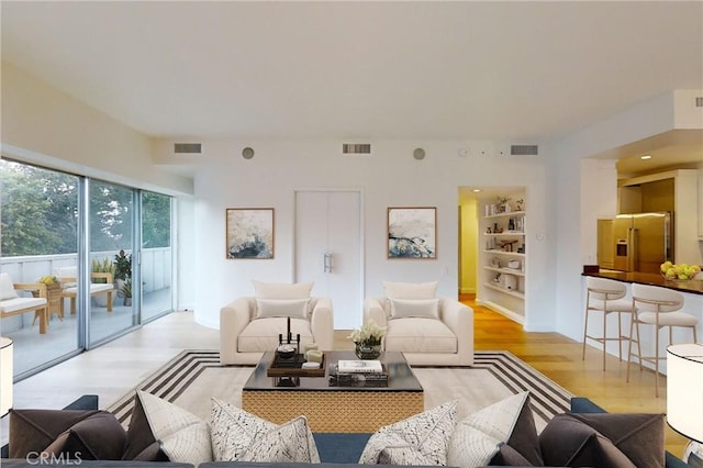 living room with visible vents, built in features, and wood finished floors