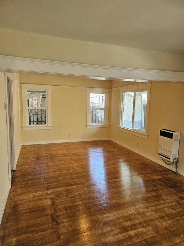 unfurnished room featuring heating unit and dark hardwood / wood-style floors