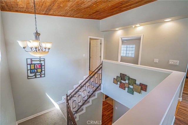 staircase with hardwood / wood-style flooring, a notable chandelier, and wood ceiling