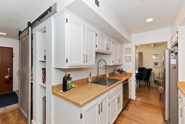 kitchen featuring a barn door, sink, light hardwood / wood-style flooring, and stainless steel appliances