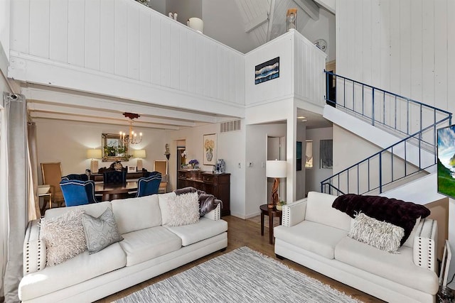 living room featuring high vaulted ceiling, wood-type flooring, a notable chandelier, and beamed ceiling