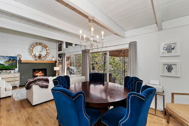 dining space featuring beam ceiling, light hardwood / wood-style flooring, and a chandelier