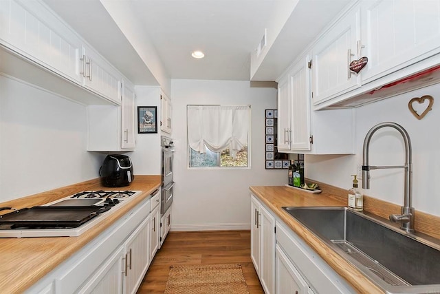 kitchen with light wood-type flooring, sink, white cabinets, white gas stovetop, and oven