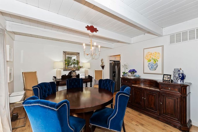 dining space with beam ceiling, light hardwood / wood-style floors, and a chandelier