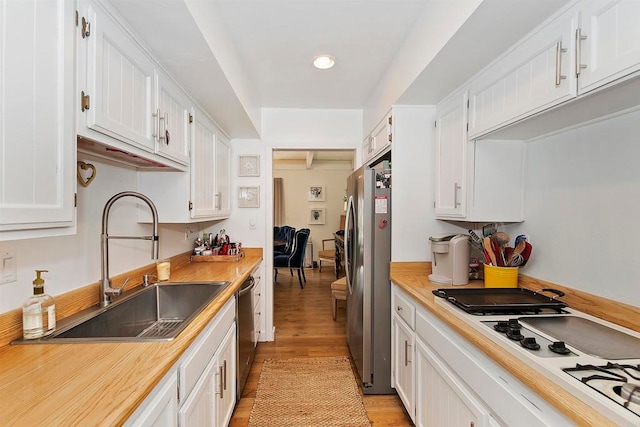 kitchen featuring stainless steel appliances, white cabinets, light wood-type flooring, and sink