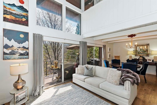 living room featuring beamed ceiling, a notable chandelier, hardwood / wood-style floors, and a high ceiling