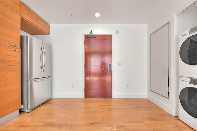 washroom with stacked washer and clothes dryer and light hardwood / wood-style flooring