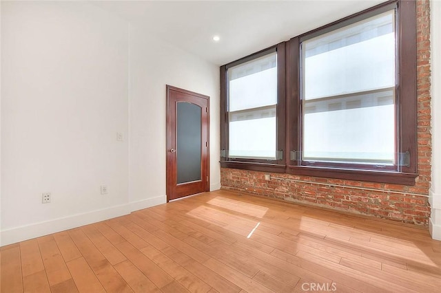 empty room with brick wall and light hardwood / wood-style floors